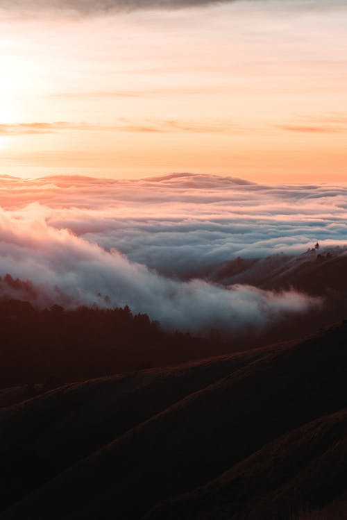 厚厚的云层在山下的夕阳的天空下 · 免费素材图片