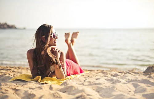女人躺在沙滩上微笑着 · 免费素材图片