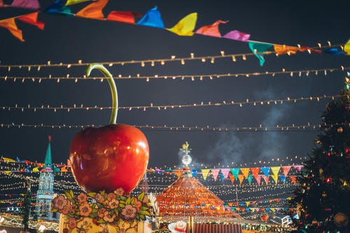 在晚上在市中心的多彩新年集市摊位屋顶上的巨型装饰苹果 · 免费素材图片