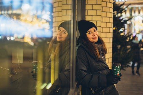 黑夹克站在玻璃窗口附近的女人 · 免费素材图片