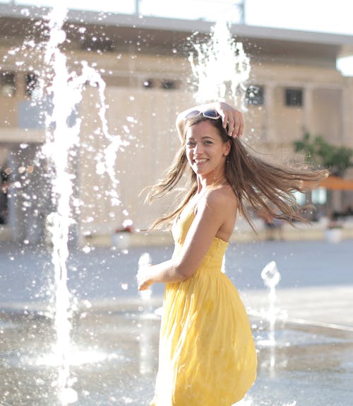黄色的裙子站在喷泉附近的女人 · 免费素材图片