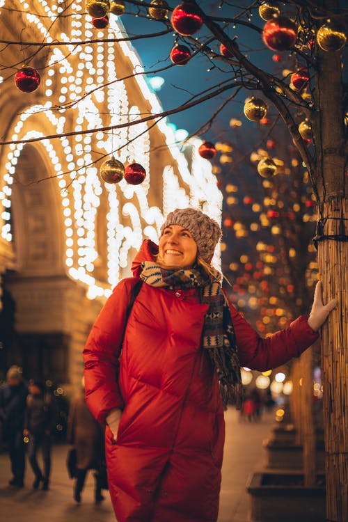 站在圣诞节球下的红色泡泡夹克的女人 · 免费素材图片