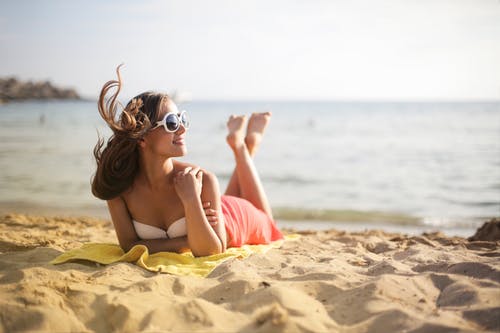 戴着墨镜躺在海滩上的女人的浅焦点照片 · 免费素材图片