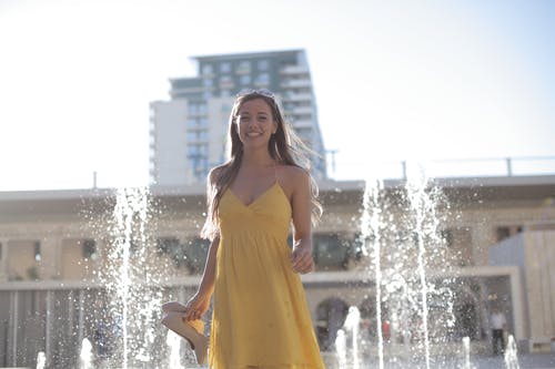 黄色意大利面条皮带礼服站在喷泉上的女人 · 免费素材图片