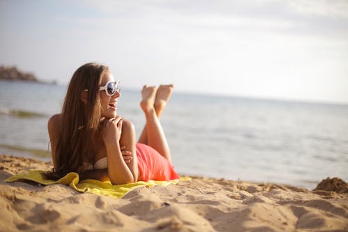 躺在海滩上的女人戴着墨镜的照片 · 免费素材图片