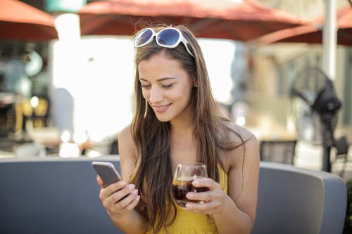 女人拿着智能手机和水杯 · 免费素材图片