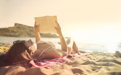 躺在海滩看书上的女人 · 免费素材图片