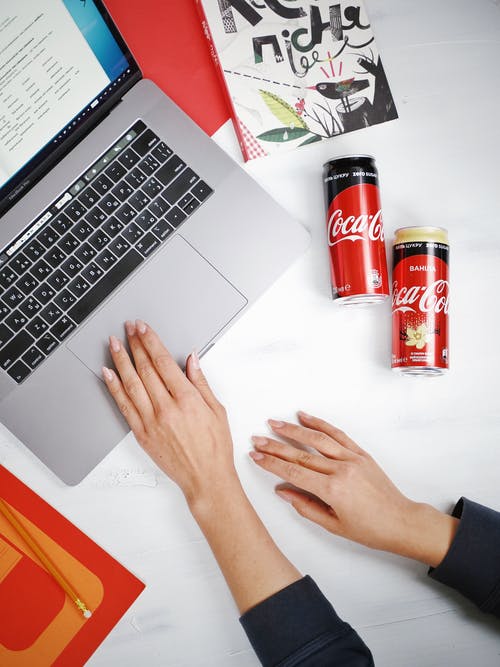 在可口可乐罐旁边使用macbook Pro的人 · 免费素材图片