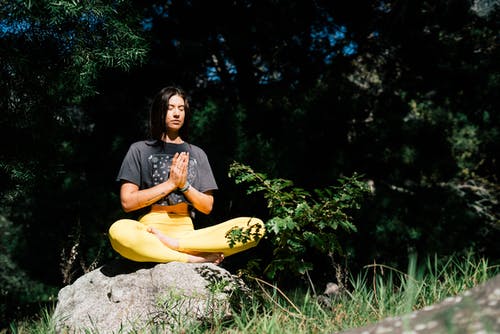 女人坐在岩石上做瑜伽的照片 · 免费素材图片