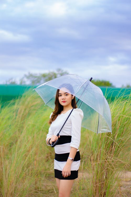 拿着伞的白色连衣裙的女人 · 免费素材图片