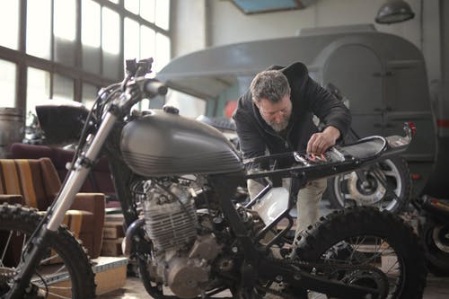 穿黑夹克的男人站在黑色的摩托车附近 · 免费素材图片
