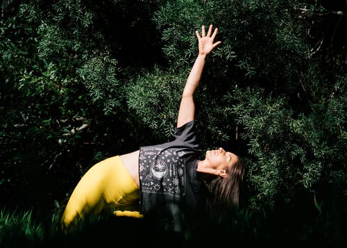 女人做暗绿色的树叶附近的瑜伽的照片 · 免费素材图片