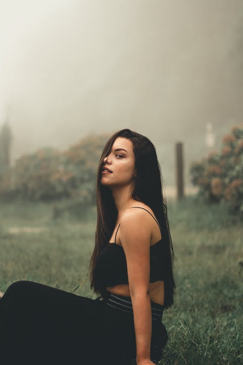 黑管顶坐在绿草地上的女人 · 免费素材图片