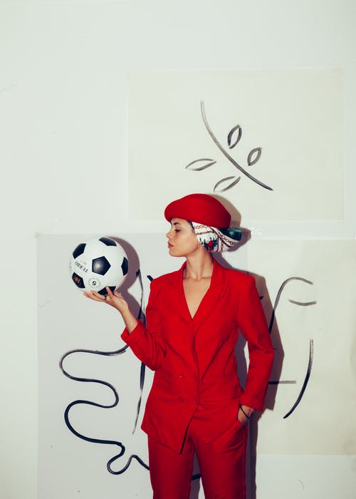 红色西装外套拿着白色和黑色的足球的女人 · 免费素材图片