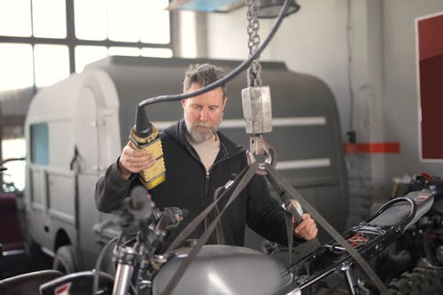 在车库中使用液压起重机的男技工 · 免费素材图片