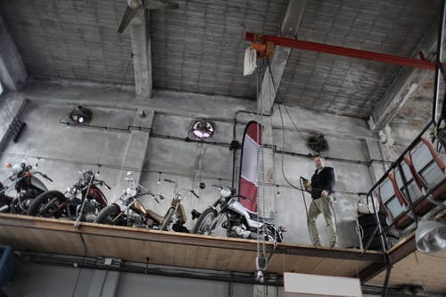 站在摩托车附近的严肃的技工一起停放在车库的特殊平台上 · 免费素材图片