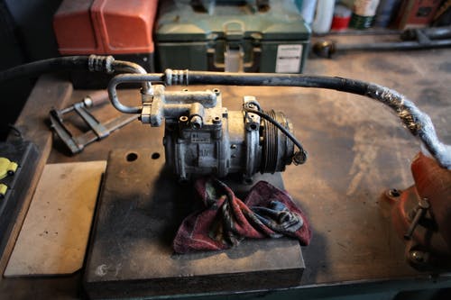 车库工作台上的金属空调压缩机 · 免费素材图片