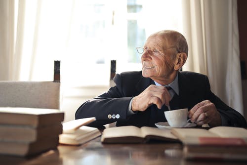 老人坐在桌旁，喝热饮料 · 免费素材图片