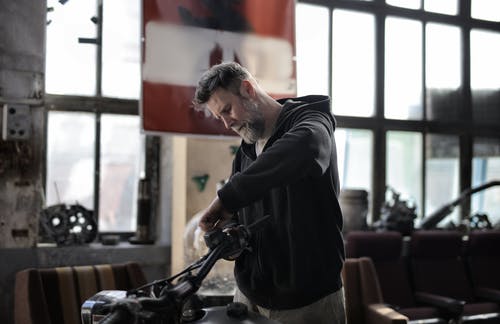 成熟的男人在车库里修理摩托车车把 · 免费素材图片