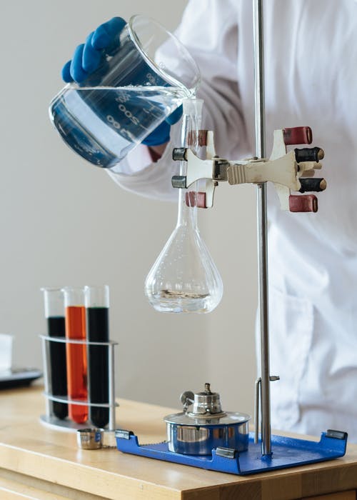 作物化学家在科学中心将透明液体倒入易碎的玻璃器皿中 · 免费素材图片
