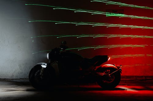 红色和黑色的摩托车停在红墙旁边 · 免费素材图片
