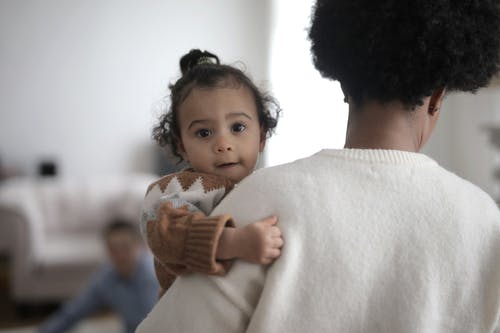 白色毛衣携带婴儿在棕色毛衣的女人 · 免费素材图片