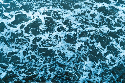 泡沫挥舞着蓝色海水的背景 · 免费素材图片