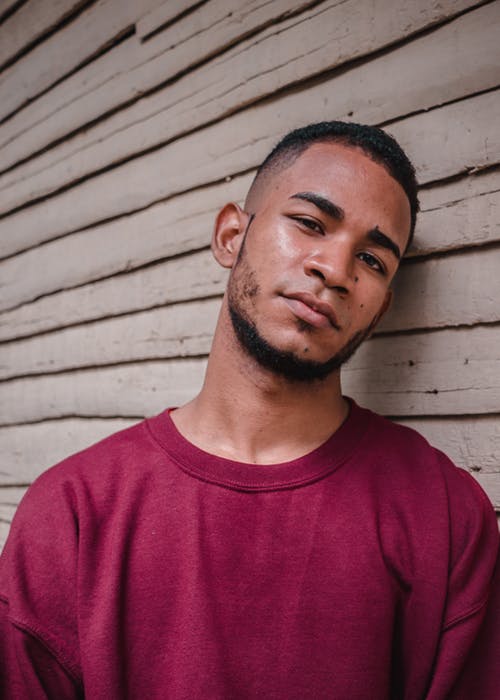 体贴的年轻民族，倚在木墙上 · 免费素材图片