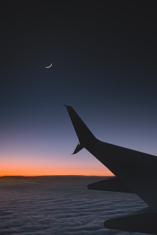 日落期间飞机飞过云层 · 免费素材图片