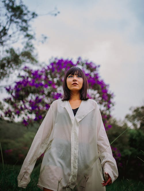 白色外套站在紫色的花田附近的女人 · 免费素材图片