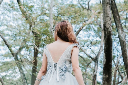 白色无袖连衣裙站在森林里的女人 · 免费素材图片