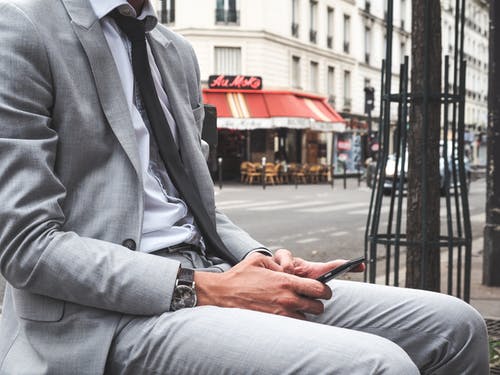 灰色西装外套和灰色西裤坐在长凳上的男人 · 免费素材图片