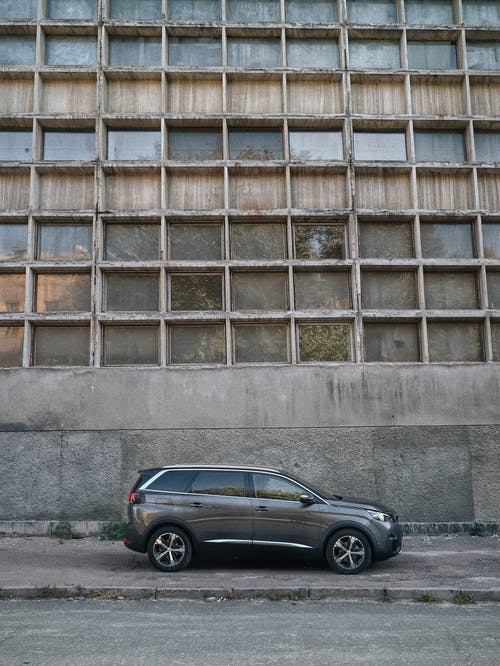 黑色轿车停在棕色混凝土建筑旁边 · 免费素材图片