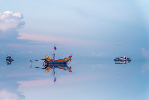 漂浮在清澈的海水中反射的渔船 · 免费素材图片