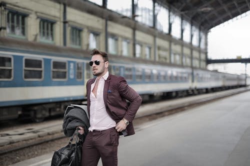 站在火车站的平台上的太阳镜的自信时尚男性旅行者 · 免费素材图片