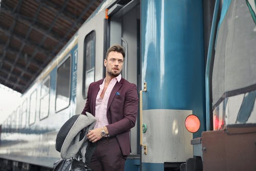 时尚男性乘客站在车站的火车附近 · 免费素材图片