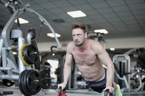在健身房里做俯卧撑的集中肌肉男 · 免费素材图片