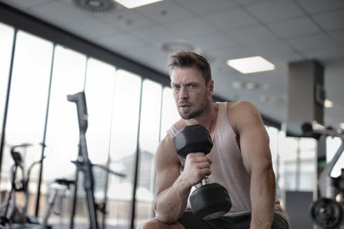 用哑铃在体育中心锻炼的肌肉健壮的男人 · 免费素材图片