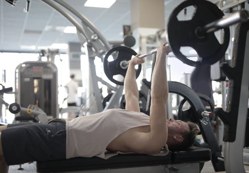 在现代健身房举重锻炼期间与重的杠铃肌肉运动员训练 · 免费素材图片