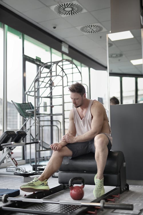 在健身房举重锻炼期间在长凳上休息的累男运动员 · 免费素材图片