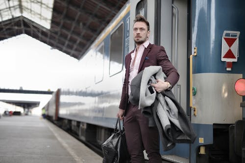 时尚的男人站在火车站与袋和外套在火车站附近 · 免费素材图片