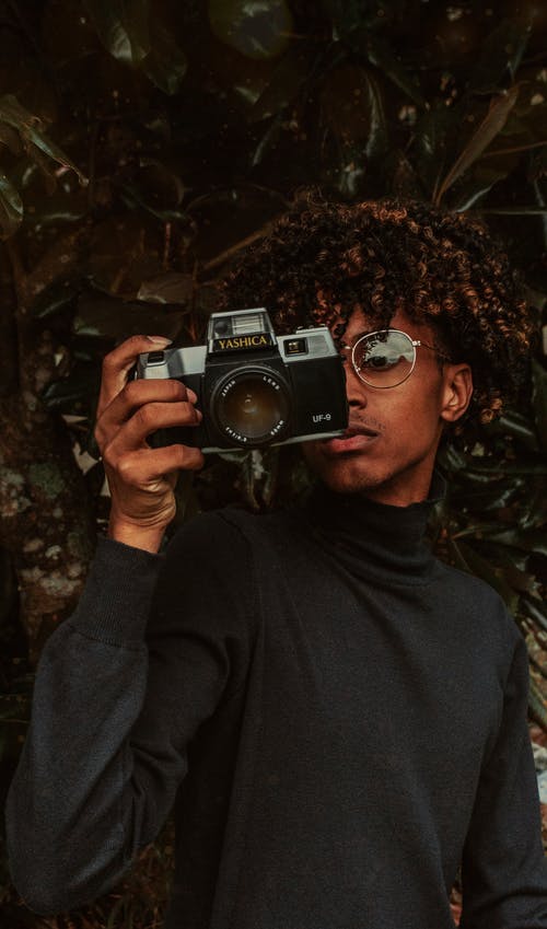 集中在花园中使用老式照片相机的黑人少年 · 免费素材图片