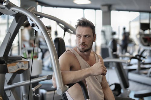 在健身房锻炼机上休息的残酷运动员 · 免费素材图片