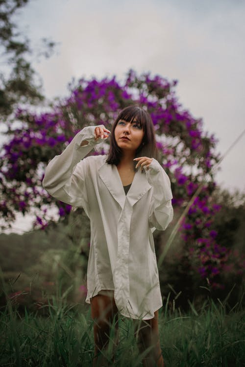 白色外套站在紫色的小花附近的女人 · 免费素材图片