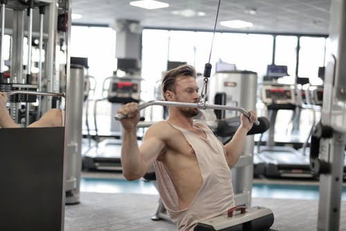 在现代健身房训练时在模拟器上练习的强壮严肃的男性运动员 · 免费素材图片