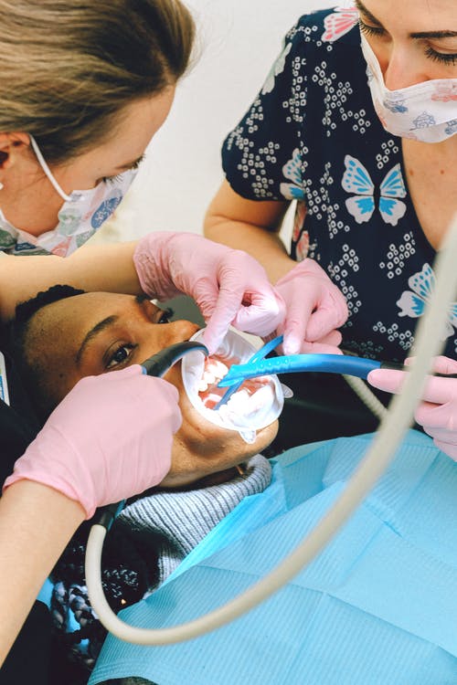女牙医在现代诊所治疗客户的牙齿 · 免费素材图片