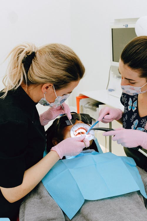 女牙医助理治疗病人的牙齿在诊所 · 免费素材图片