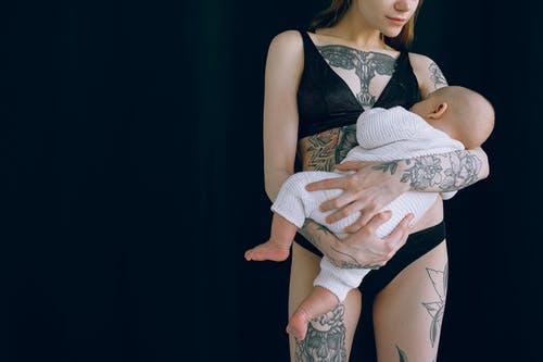 匿名的年轻母亲在拍摄照片时拥抱新生婴儿 · 免费素材图片