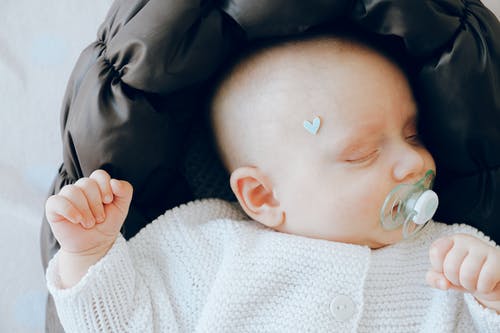 可爱的新生婴儿奶嘴睡在柔软的婴儿床 · 免费素材图片