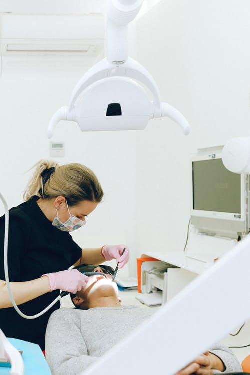 女牙医治疗男性客户在诊所的牙齿 · 免费素材图片